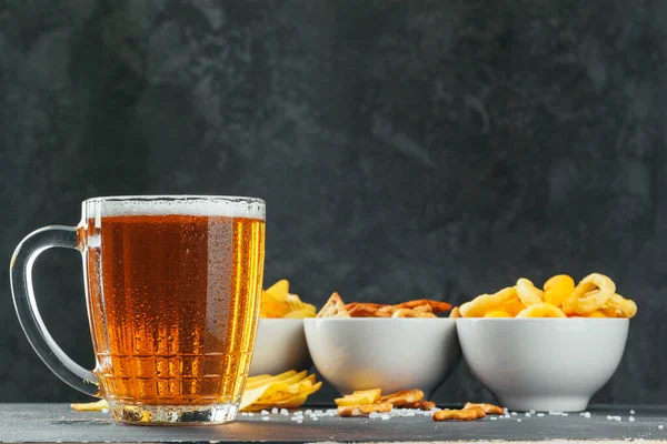 Cerveja Lager e lanches na mesa de pedra. Cracker, chips vista lateral — Fotografia de Stock