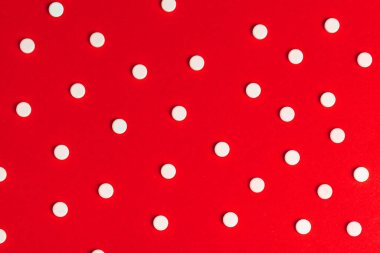 Kırmızı arka planda ilaç haplarının üst görünümü