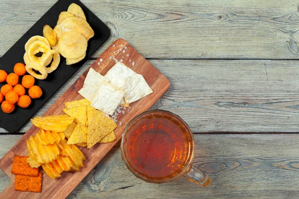 Cerveza y aperitivos en mesa de madera. — Foto de Stock