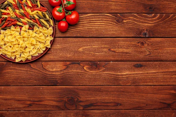 Pasta en ingrediënten op houten achtergrond met kopieerruimte. Bovenaanzicht. — Stockfoto