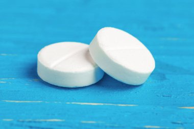 Dökülmüş beyaz tabletlerle parlak mavi ahşap arka plan