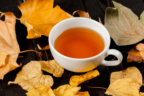 Tasse Tee und Herbstblätter auf dem Tisch — Stockfoto