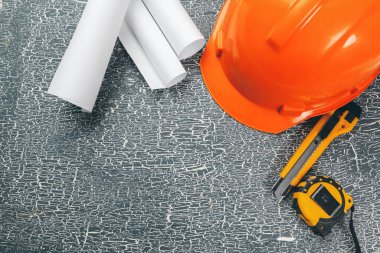 Planları, pusulası, kalemi ve kaskı olan mühendis işyeri