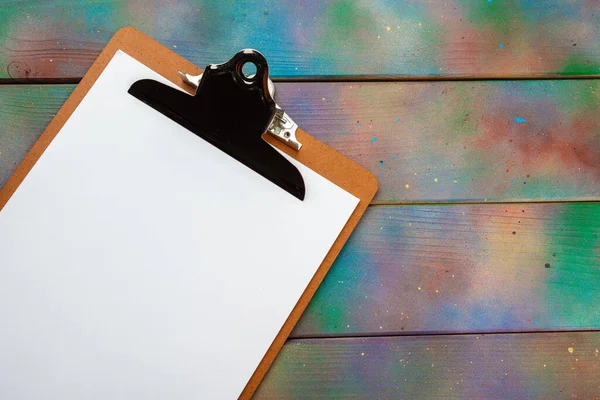 Blank paper on wooden clipboard on dark wooden floor background