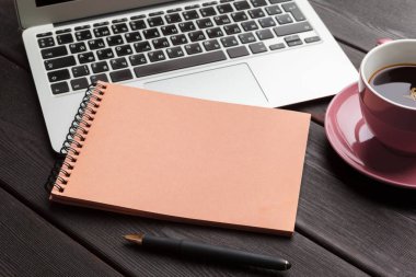 Boş dizüstü bilgisayarı ve kahve fincanı olan ofis masası.