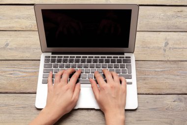 Dizüstü bilgisayarın üst görünümünde yazı yazan kadın elleri