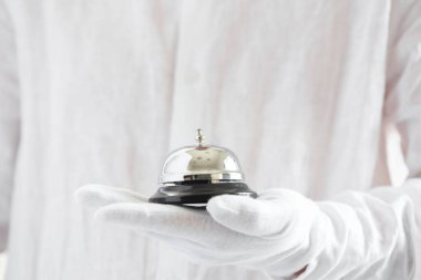 Birinci sınıf hizmet. Otel zilini tutan beyaz eldivenler