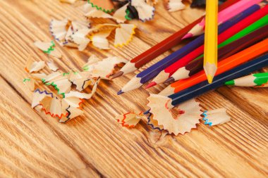 Ahşap arka planda renkli kalemler ve kalem kesimleri yakın