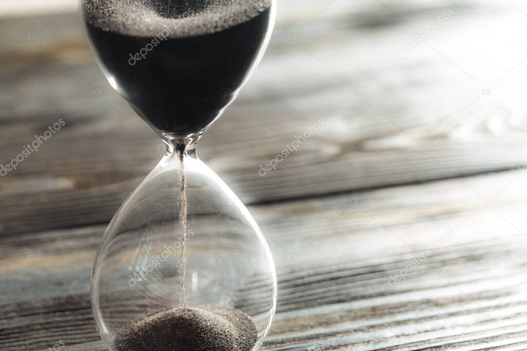 Modern hourglass on wooden background creative photo.