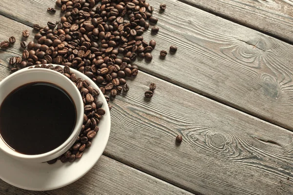 Чашка кофе и бобы на деревянном фоне — стоковое фото