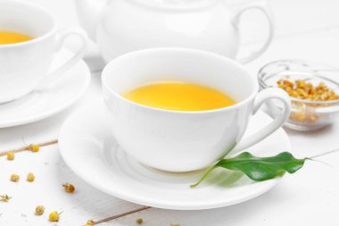 Çaydanlık ve fincanlar beyaz ahşap arka planda.