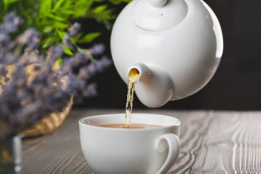 Ahşap masada bir fincan siyah çay ile camdan bir çaydanlık.