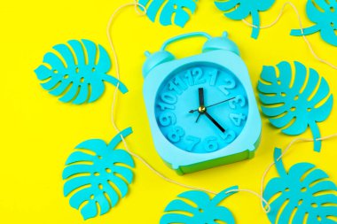 Çalar saat yaratıcı fotoğrafıyla tropik yapraklar..