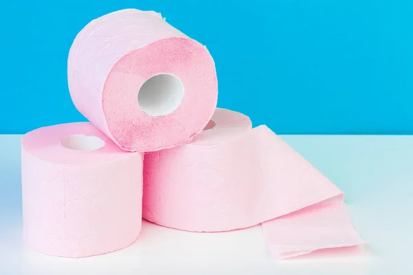 Tres rollos de papel higiénico aislados en mesa blanca con fondo azul — Foto de Stock