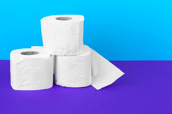 Rollos de papel higiénico aislados sobre mesa blanca con fondo púrpura — Foto de Stock