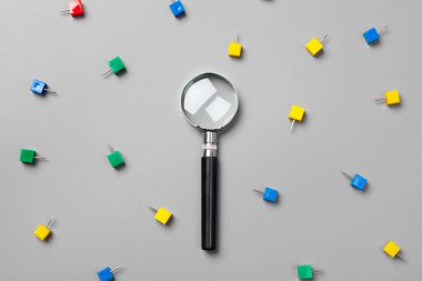 Gri arkaplanda ataç olan büyüteç. Minimalizm kavramı.