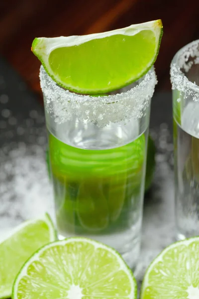 Tequila Silver Shots mit Limettenscheiben und Salz auf Holzbrett — Stockfoto