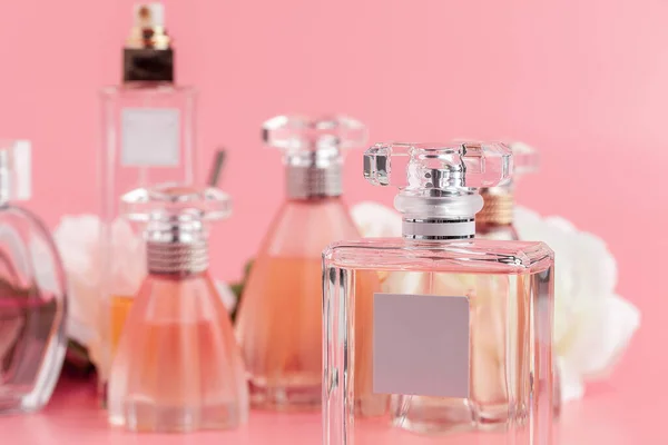 Parfum fles met rozen op roze stof achtergrond — Stockfoto