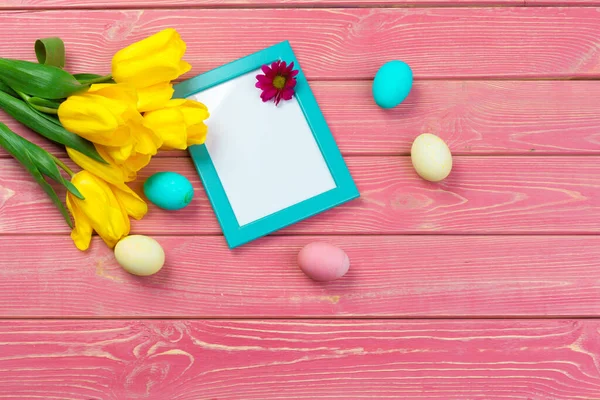 Easter concept. Wooden frame with easter eggs and tulips on colorful background — Stock Photo, Image