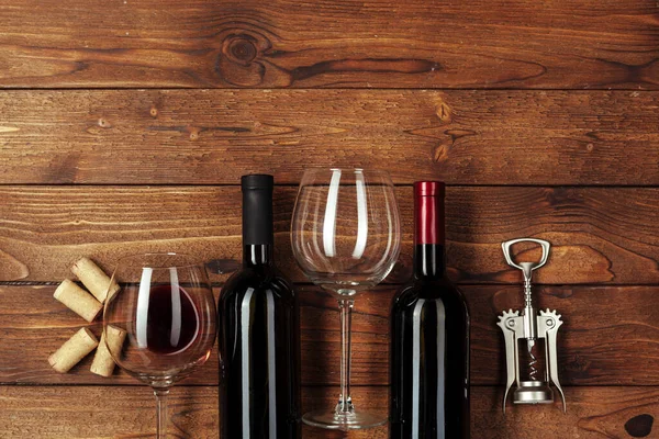 Red wine bottle, wine glass and corkscrew on wooden table background — Stock Photo, Image