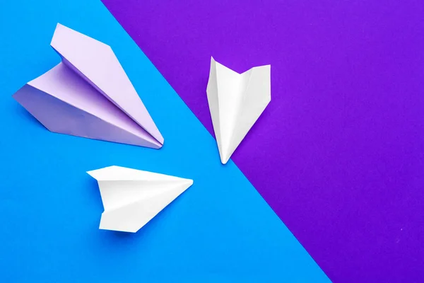 Avión de papel blanco sobre un fondo de papel azul y púrpura — Foto de Stock