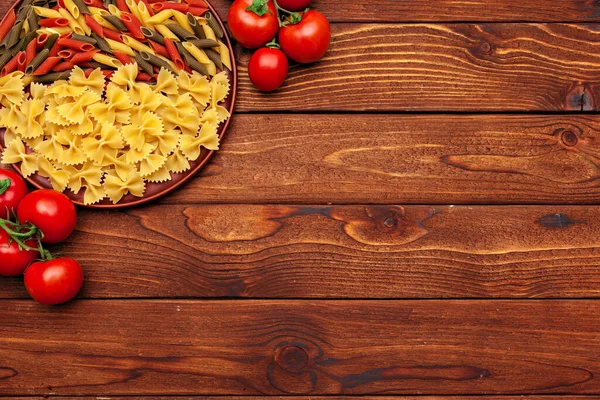 Pasta en ingrediënten op houten achtergrond met kopieerruimte. Bovenaanzicht. — Stockfoto