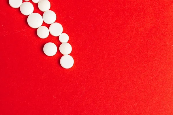 Bílé pilulky vylévání ze svržené bílé láhve na červeném pozadí — Stock fotografie