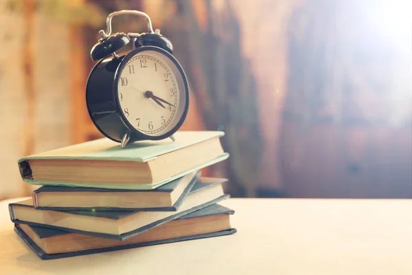 Despertador cerca de libros en la mesa — Foto de Stock