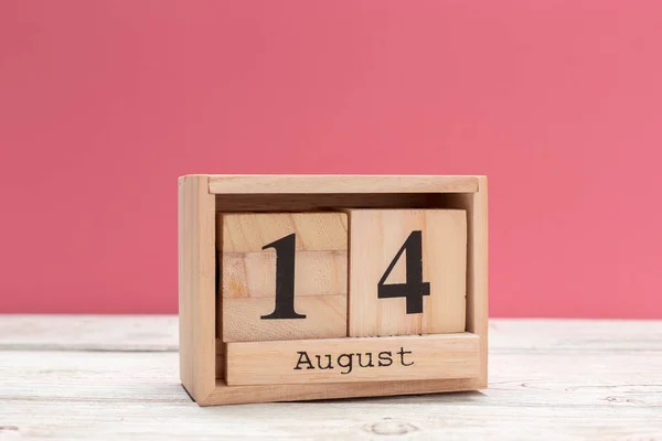 wooden cube shape calendar for august 14 on wooden tabletop