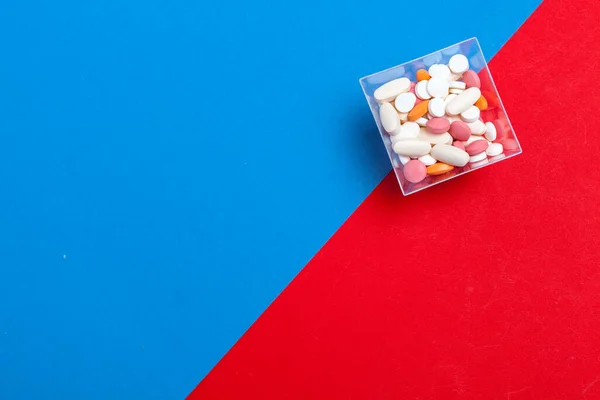 Mnohobarevné pilulky na modrém a červeném pozadí. Lékařský koncept. Textura. — Stock fotografie