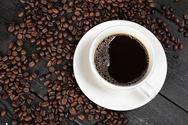Чашка кофе и бобы на деревянном фоне — стоковое фото