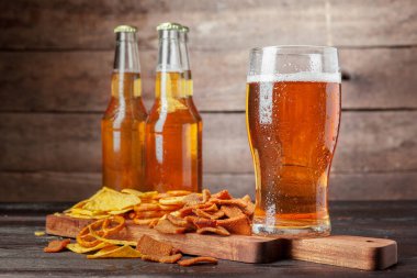 Lager beer and snacks on wooden table. Nuts, chips, pretzel clipart