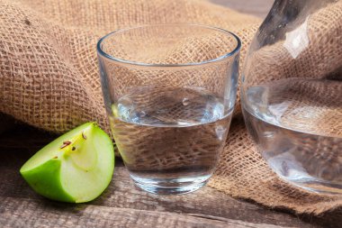 Temiz suda elma dilimleri ve ahşap bir masada taze bir elma ile beslenme içeceği.