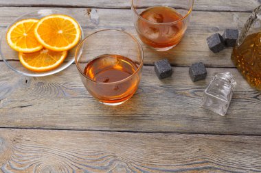 Koyu ahşap arka planda portakal meyveli viski bardağı.