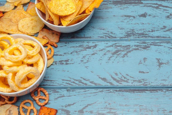Snacks salados. Pretzels, patatas fritas, galletas saladas sobre fondo de madera. Productos poco saludables — Foto de Stock