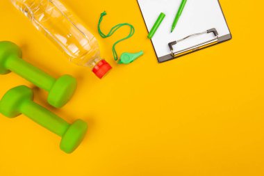 Sarı arka planda spor salonu ekipmanlı bir pano.