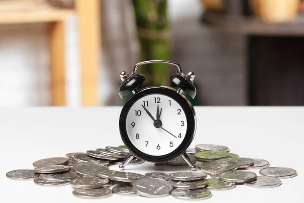 Reloj despertador y monedas de dinero sobre la mesa. — Foto de Stock