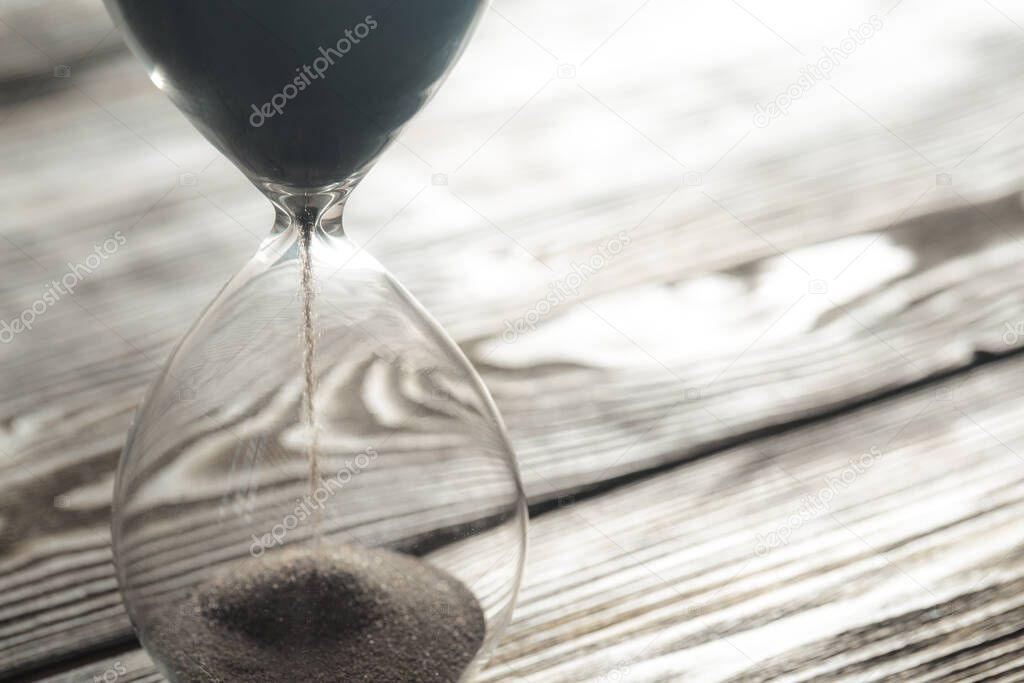Modern hourglass on wooden background. Close up.