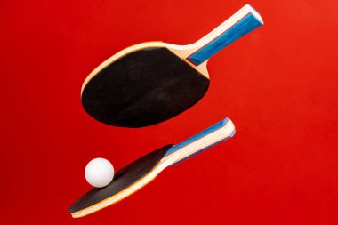 Kırmızı arkaplanda siyah ping pong raketleri