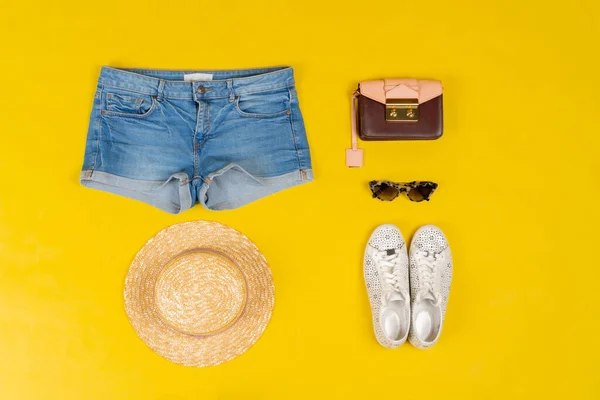 Conjunto de roupas femininas e acessórios em fundo amarelo brilhante — Fotografia de Stock