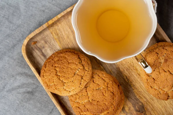 Xícara de porcelana branca de biscoitos de chá e aveia em uma mesa — Fotografia de Stock