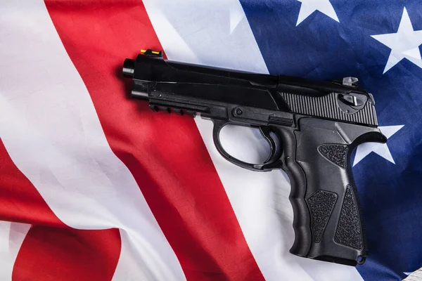 Amerikan bayrağında duran tabanca. Silah sorunu kavramı