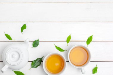 Çaydanlık ve fincanlar beyaz ahşap arka planda.