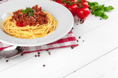 Etli makarna, domates sosu ve sebzeler masada.