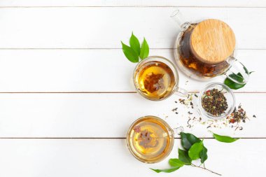 Çaydanlık ve fincanlar beyaz ahşap arka planda.