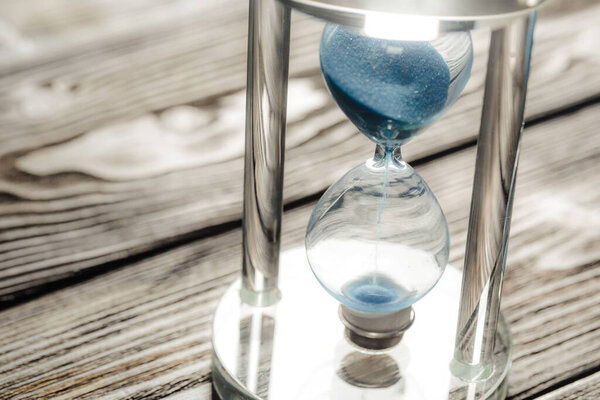 Modern hourglass on wooden background. Close up.