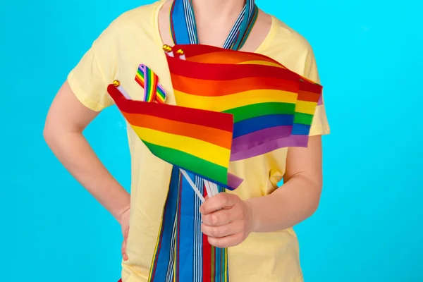 Young unrecognizable woman holding small LGBT flag on bright color background — Stock Photo, Image