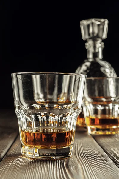 Eski ahşap masada viski bardağı ve şişe.