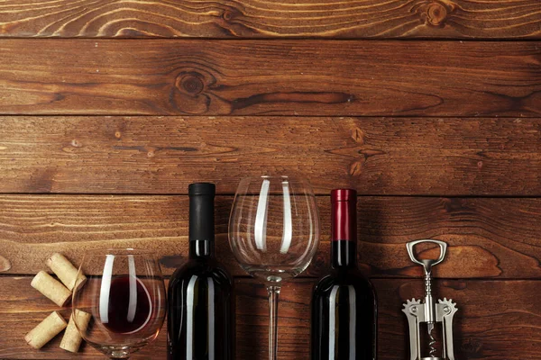 Red wine bottle, wine glass and corkscrew on wooden table background — Stock Photo, Image