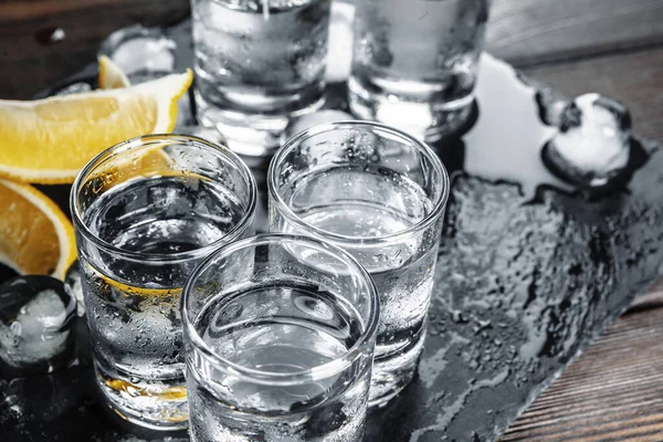 Vodka en vasos de chupito sobre fondo rústico de madera — Foto de Stock